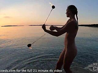 Nude fire dancer performs on usa beach at sunset
