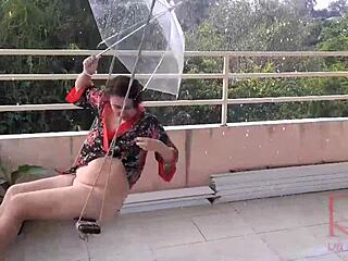 Depraved housewife swings without panties hiding from rain under umbrella. Full video shows wild gymnast moves.