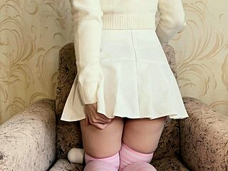 A girl in a white skirt masturbates with a vibrator