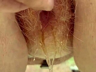 Redhead beauty pees through her lush hairy pussy in close detail